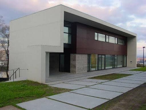 Casa Rectoral y centro parroquial de San Pedro de Visma, edificio moderno en A Coruña, con un camino de concreto y césped, diseñado por Fernández Madrid e Iglesias Pereira